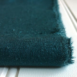 close-up of folded teal green raw silk noil